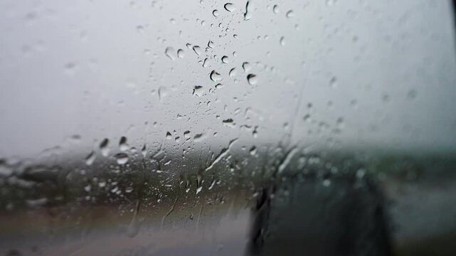Close Up of Rain on Car Window with Blurred Lights and Wet Glass