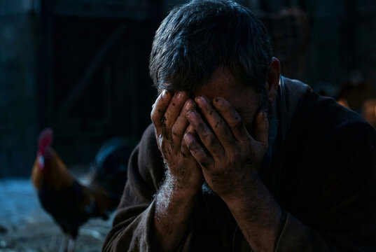  Dramatic biblical scene of the Apostle Peter weeping in bitter regret, covering his face with dirty hands after denying Christ, with a rooster in the dark background