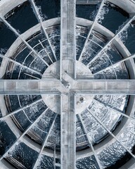 An aerial view showcasing a water treatment plant and its intricate structure. The circular design with radiating pathways creates an intriguing geometric pattern