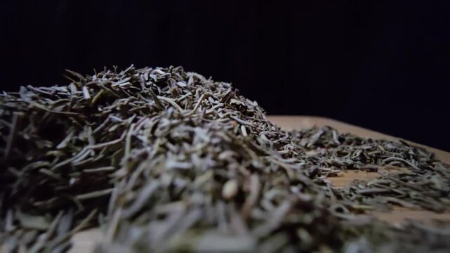 Extreme macro close-up of dried thyme leaves on a wooden surface with a black background. Slow cinematic probe lens movement revealing intricate textures and herbal details.