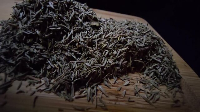 Extreme macro close-up of dried thyme leaves on a wooden surface with a black background. Slow cinematic probe lens movement revealing intricate textures and herbal details.