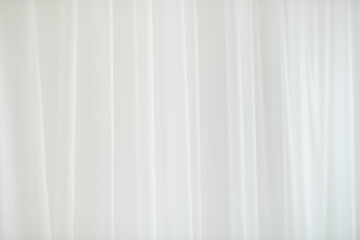 Fototapeta premium Soft white fabric background with subtle vertical folds and gentle texture, creating a clean, airy, and minimal backdrop ideal for product displays, branding, or copy space