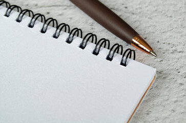 Obraz premium Clean white spiral notebook on textured surface with pencil at top edge, with customizable space on notebook for text or ideas