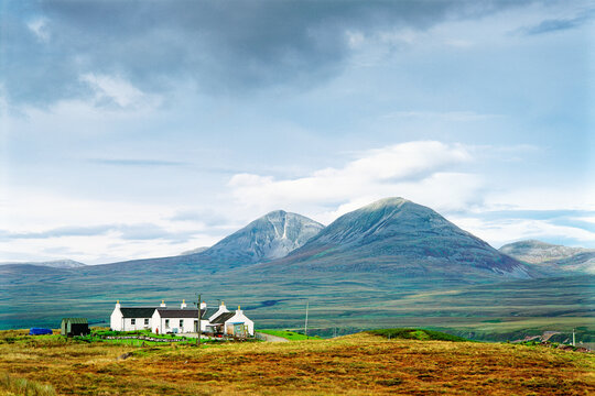The Paps of Jura mountains on the Isle of Jura seen behind cottage on the north coast of Islay in the Inner Hebrides, Scotland