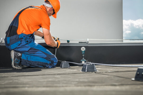 Worker Installs Lightning Protection Equipment on a Rooftop in Daylight