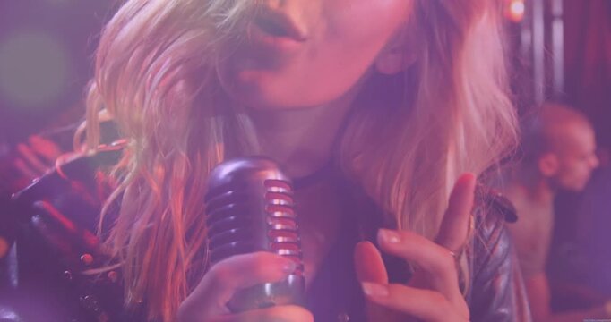 Female lead singer cupping vintage mic and singing, building intensity for club music moment