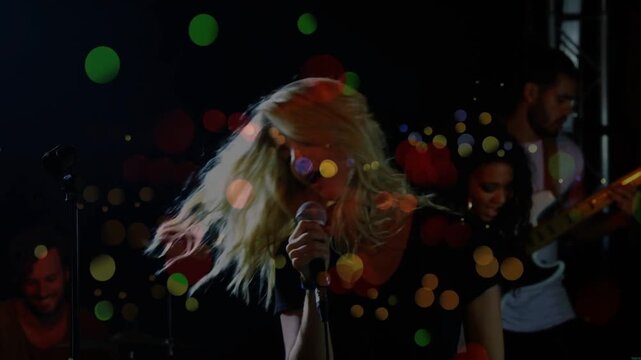 Vertical video: Singer brushing hair, singing into wired mic as bokeh growing bass playing mood