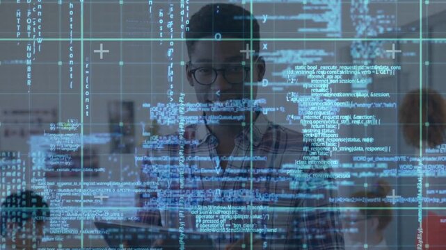 Male developer studying tablet in open office, activating blue code grid testing AR obscuring face