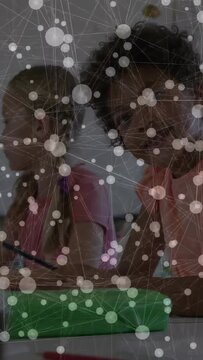 Vertical video: Girls reaching stylus to green case, causing overlay fading and engaging learning