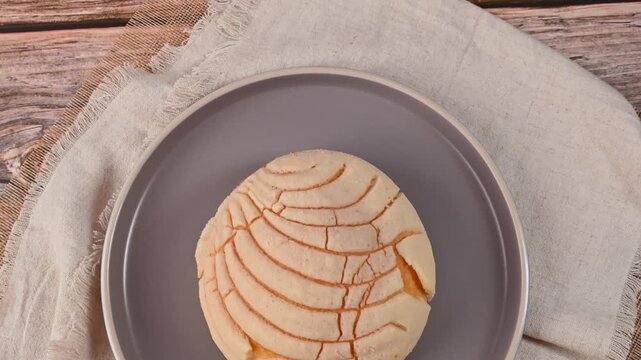 Authentic Mexican sweet bread bun (concha) on a wooden table with linen napkin