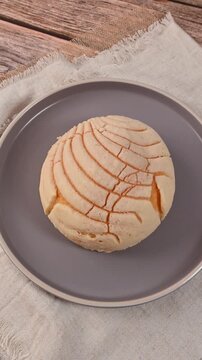 Typical Mexican bread, a vanilla concha served on a modern gray plate on linen cloth