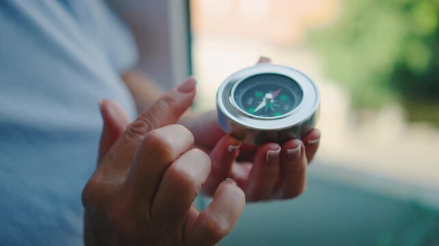 Elderly woman holding a compass near a window during daylight hours in a cozy indoor setting