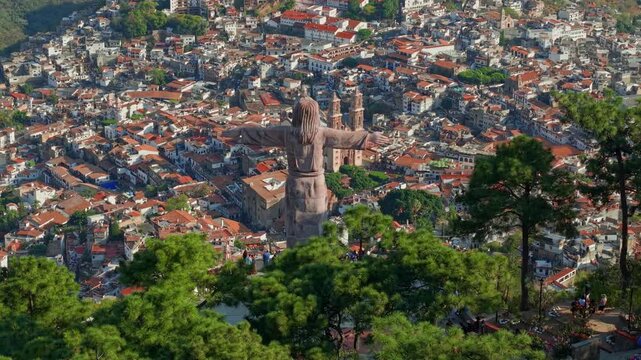 Aerial telephoto view of the Monumental Christ of Taxco overlooking the town of Taxco and the temple of Santa Prisca, with tiled roofs and white colonial houses, Guerrero, Mexico
