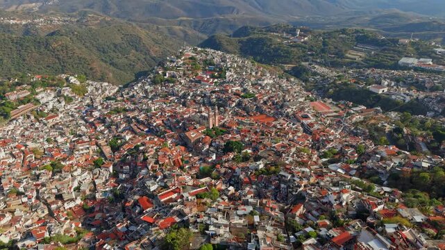 Establishing aerial view of the city of Taxco de Alarcon in Guerrero, Mexico, with the Sierra mountains in the background at dawn with a thin mist.