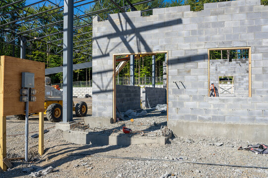 Concrete masonry unit, cmu, blocks wall under construction, with window and door openings. 
