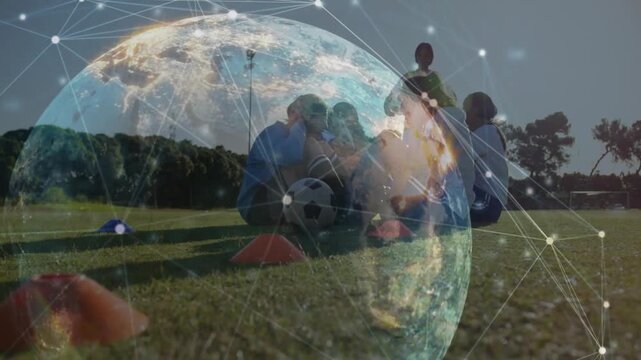 Coach signaling soccer drill while team syncing crunches near cones and ball, globe overlay pulsing