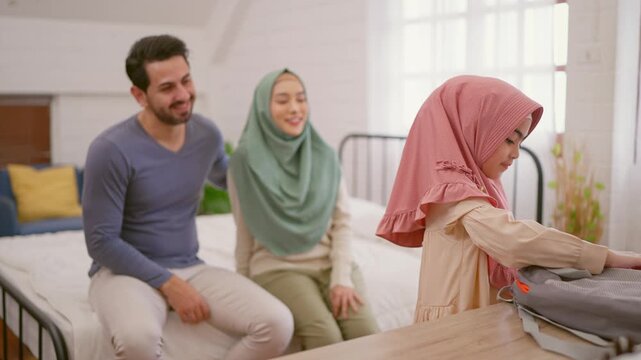Asian Muslim mother prepare school backpack to young daughter at home.