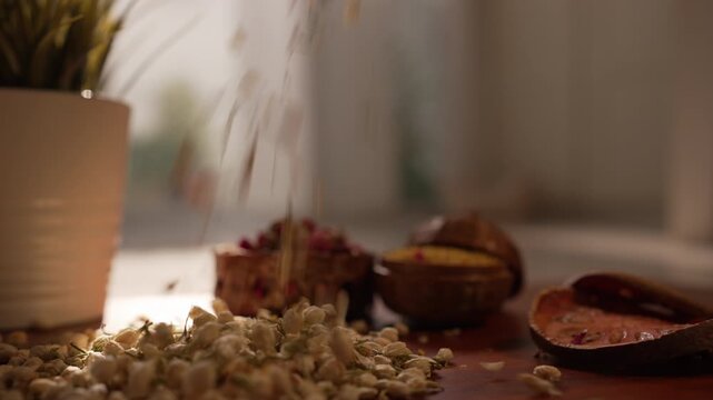 Cinematic shot of dried jasmine buds pouring down in warm soft diffused natural light, showcasing delicate organic textures, abundance, and calm aesthetics with dried bael and wooden pots in the backg