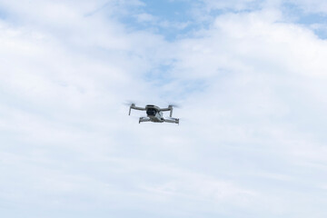 Fototapeta premium Close view of a drone flying in the sky with clouds, symbolizing aerial imaging, modern technology and remote controlled flight.