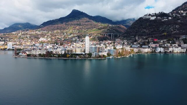 Aerial: Lake Geneva, Montreux cityscape and mountains during the day in Canton of Vaud, Switzerland, orbit drone shot