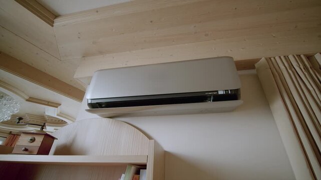 Modern split system air conditioner unit mounted on wall in rustic wooden room with soft lighting