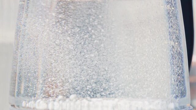Extreme close-up of bubbles rising and water boiling rapidly inside a modern glass electric kettle. Detailed view of evaporation and bubbling process in high definition.