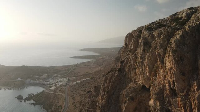 Stunning aerial perspective of a steep cliff face overlooking a serene coastal village finiki on karpathos island at sunrise