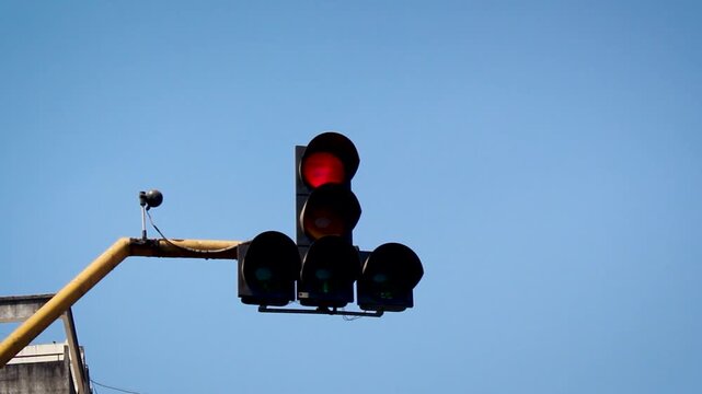 Red traffic signal light at road intersection in India against clear blue sky, urban transport control system showing stop signal, road safety regulation and city traffic management.