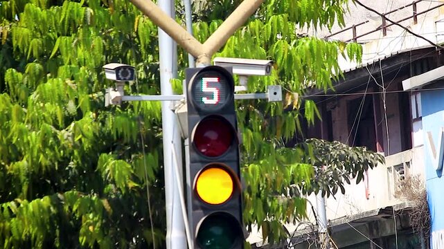 Traffic signal countdown changing from green to yellow and red on urban road. Useful for transport, road safety, smart city and traffic control content.