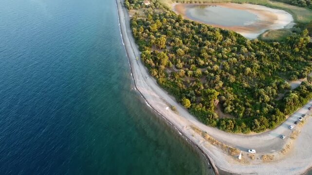 Cinematic drone shot of Asproneri beach near Kamena Vourla. The video starts with a boat and reveals the unique coastline and the adjacent Vromolimni lagoon. Perfect for travel and nature films.