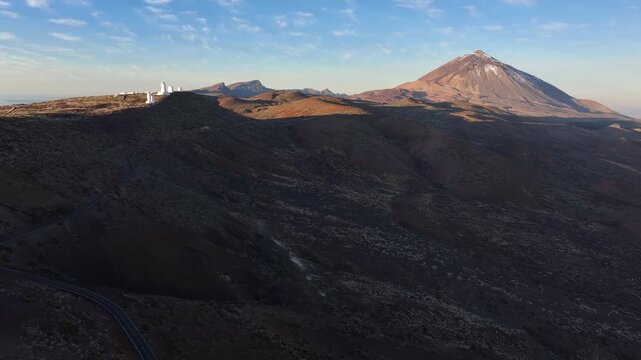 A winding road leads past the Teide observatory with Teide volcano in the background. Canary Islands. Tenerife. Aerial video.
