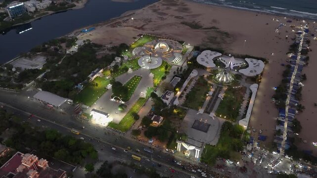 Aerial night view of Anna and MGR Memorials along Marina Beach in Chennai, showcasing illuminated architecture, landscaped gardens, and bustling coastal city life beside the Bay of Bengal.