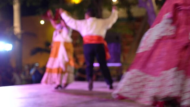 Mexican folkloric dancers performing traditional zapateado on outdoor stage during evening cultural festival with colorful dresses