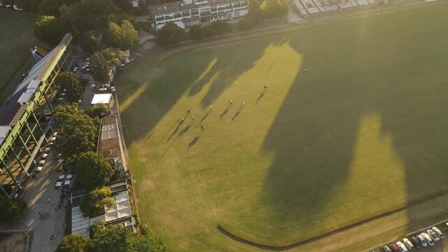 Aerial view of polo field with players and horses during golden hour