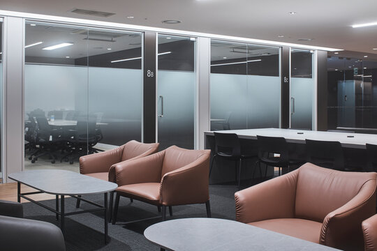 Office lounge with pink chairs and glass walls in modern corporate interior