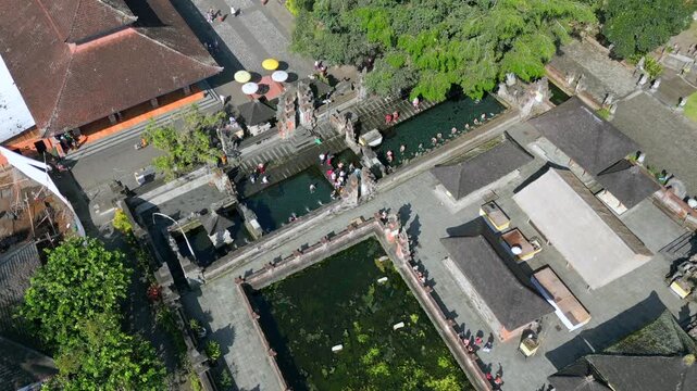 Aerial view of Tirta Empul Temple in Ubud, Bali, Indonesia with people performing traditional water purification ritual. Famous spiritual and cultural landmark.