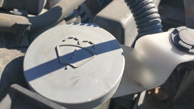 Windshield washer fluid reservoir cap with wiper icon in car engine