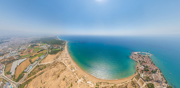 Side, Manavgat, Turkey. Wide aerial view of ancient peninsula and Buyuk Plaj (East Beach) with golden sand, turquoise water, archaeological ruins on summer day. Aerial view