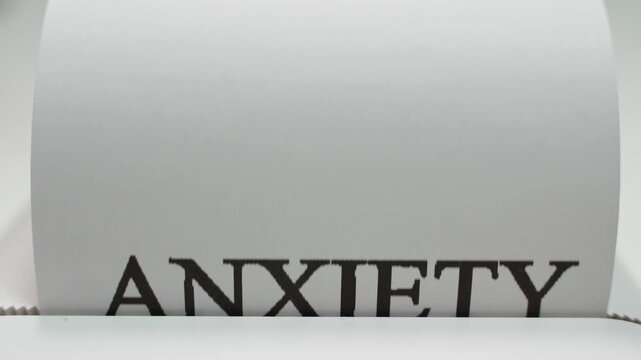 Word ANXIETY being printed close-up on white paper
