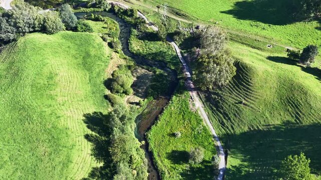 Top-down view of the crystal clear Te Waihou stream winding through lush green hills. A peaceful nature trail in the Waikato region, New Zealand.
