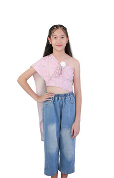 Young Asian girl wears traditional pink Thai sabai top paired with denim jeans, confidently striking pose against white background.