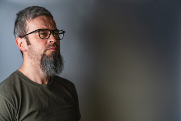 Fototapeta premium Man with glasses stands in profile with serious expression in studio