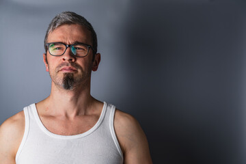 Fototapeta premium Man with glasses and goatee stands against a gray backdrop