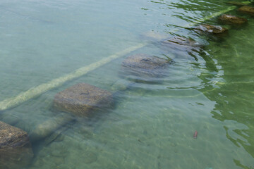 Naklejka premium Square concrete stepping stones create a peaceful path across a clear, shallow river with gentle ripples. concrete box to hold pipes in the sea