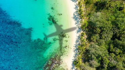 Aerial view of shadow passenger plane silhouette and sandy beach blue sea with waves at sea beach summer vacation sea travel concept	
