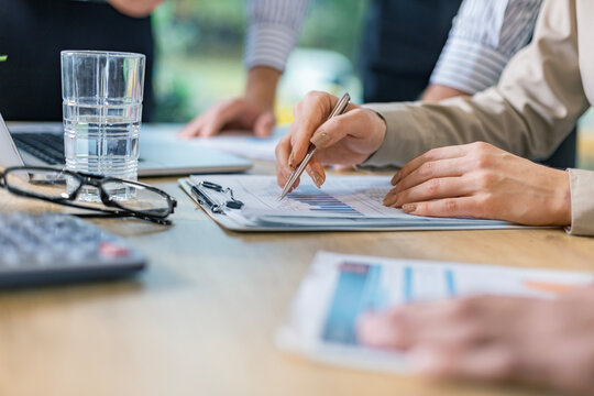 Unrecognizable business person analyzing graphs and taking notes.