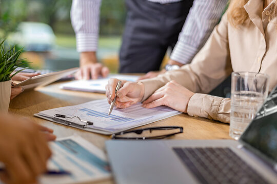 Unrecognizable business person analyzing graphs and taking notes.