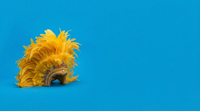 Yellow feathered headdress on blue background. Traditional festival costume accessory for cultural dances and celebrations