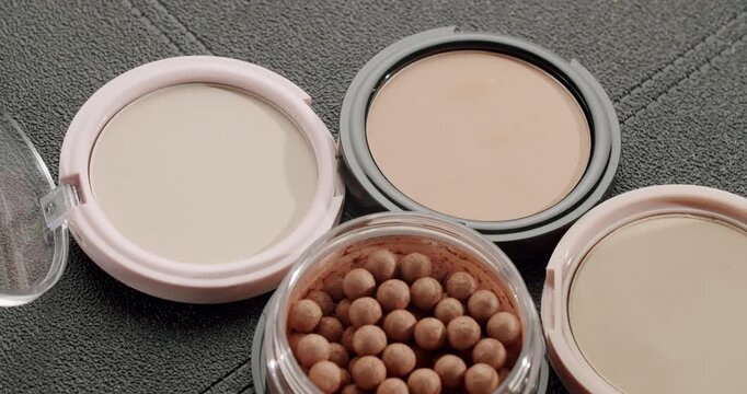 Top view of a makeup collection with various face powders and bronzing pearls on a textured background, representing the beauty industry, skincare, and cosmetic products for a perfect complexion