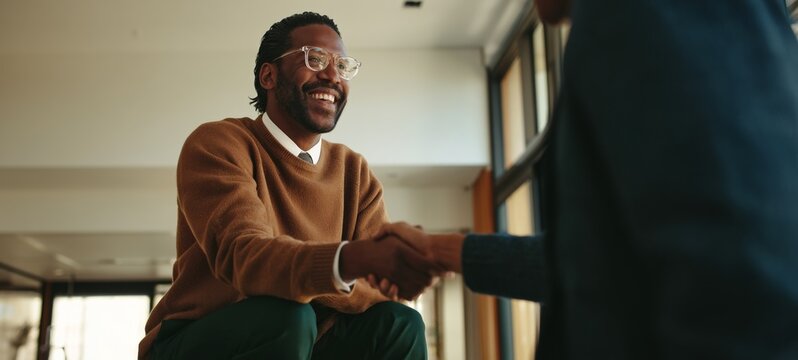 African-American Man in Sweater Sitting, Smiling and Shaking Hands